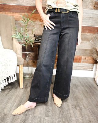 Women's black high-rise wide leg jeans with front seam detailing and cuffed hem, styled with neutral mules for a versatile boutique outfit perfect for work, weekends, and everyday wear.