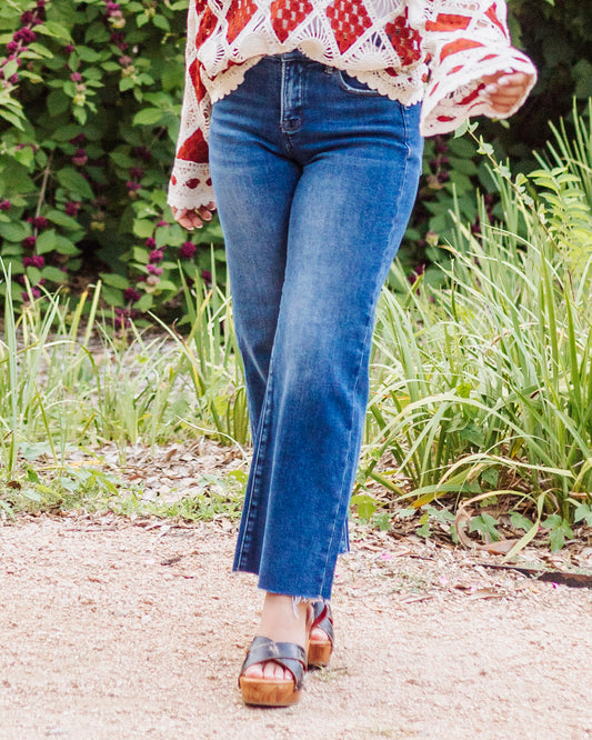 Close-up of women’s high-rise straight leg jeans with raw hem detail, styled with platform sandals and a crochet boho blouse.