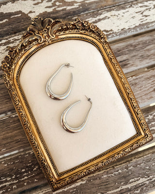 Polished silver teardrop hoop earrings featuring a sculptural open design and sleek curved silhouette, perfect for modern everyday jewelry at MaKenzie Layne Boutique.
