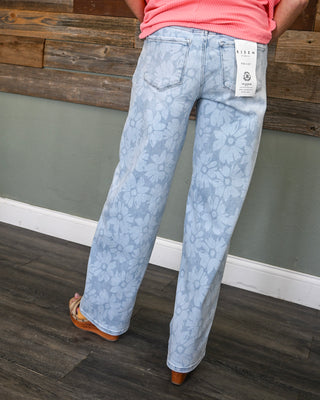 Women’s light wash straight leg jeans with allover floral print and back pockets, styled with a bright ribbed top for a playful boho boutique look