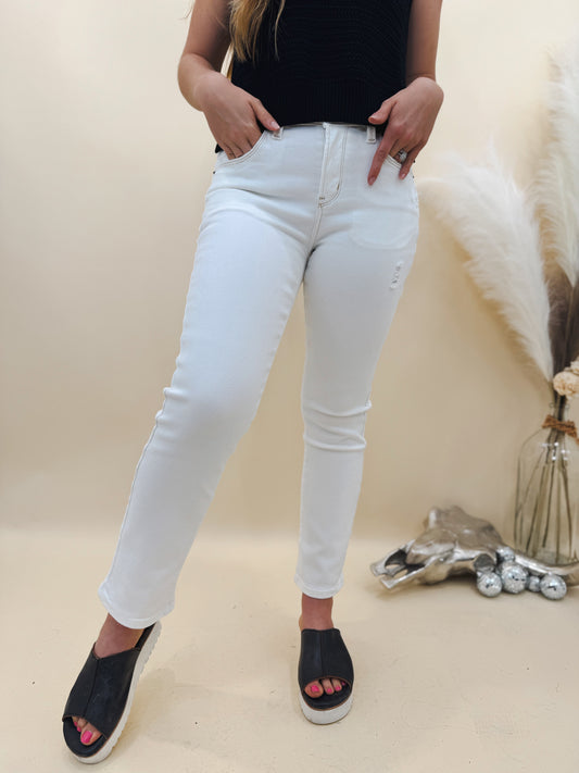 Woman wearing high-rise white skinny jeans styled with a black knit top and black platform slides. A clean, polished summer outfit perfect for day or night.