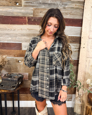Women's black and cream plaid button-down flannel shirt with chest pocket, rolled sleeves, and relaxed fit, styled with black lace-trim shorts at MaKenzie Layne Boutique.