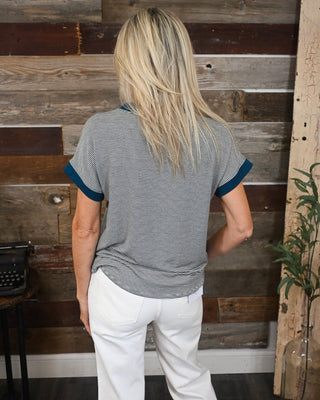 Women’s black and white micro striped short sleeve top with contrasting teal cuffs, styled with white jeans for an easy casual boutique look.