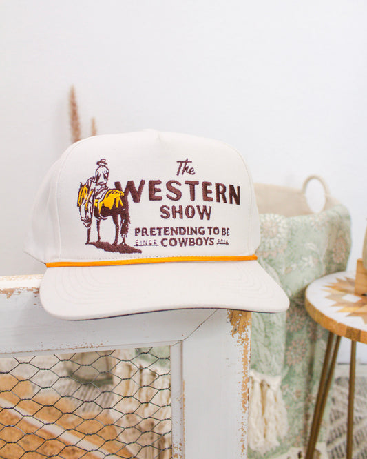 Cream Sendero Provisions Co. cap with “The Western Show: Pretending to Be Cowboys Since 2014” embroidered design featuring cowboy and horse artwork.