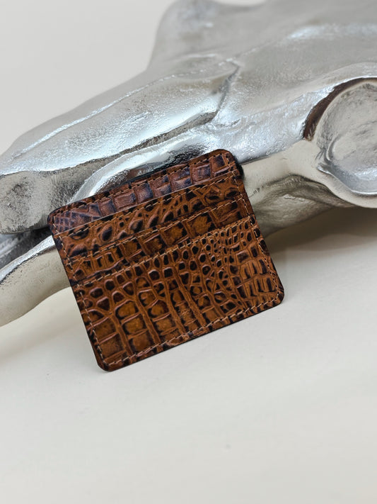 Brown crocodile-embossed leather card holder with a sleek, slim design—stylish and functional minimalist wallet shown against a silver Western-inspired backdrop.
