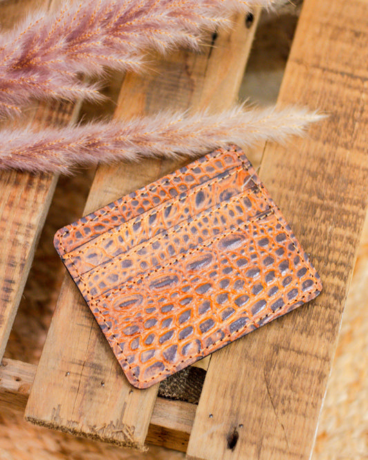 Genuine leather crocodile embossed card holder wallet in rustic brown with multiple slots for cards, styled on a wooden surface with pampas grass decor.