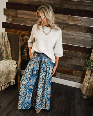 Women’s blue boho print wide leg pants with a relaxed flowy fit and elastic waist, styled with an ivory knit sweater for an elevated casual outfit.